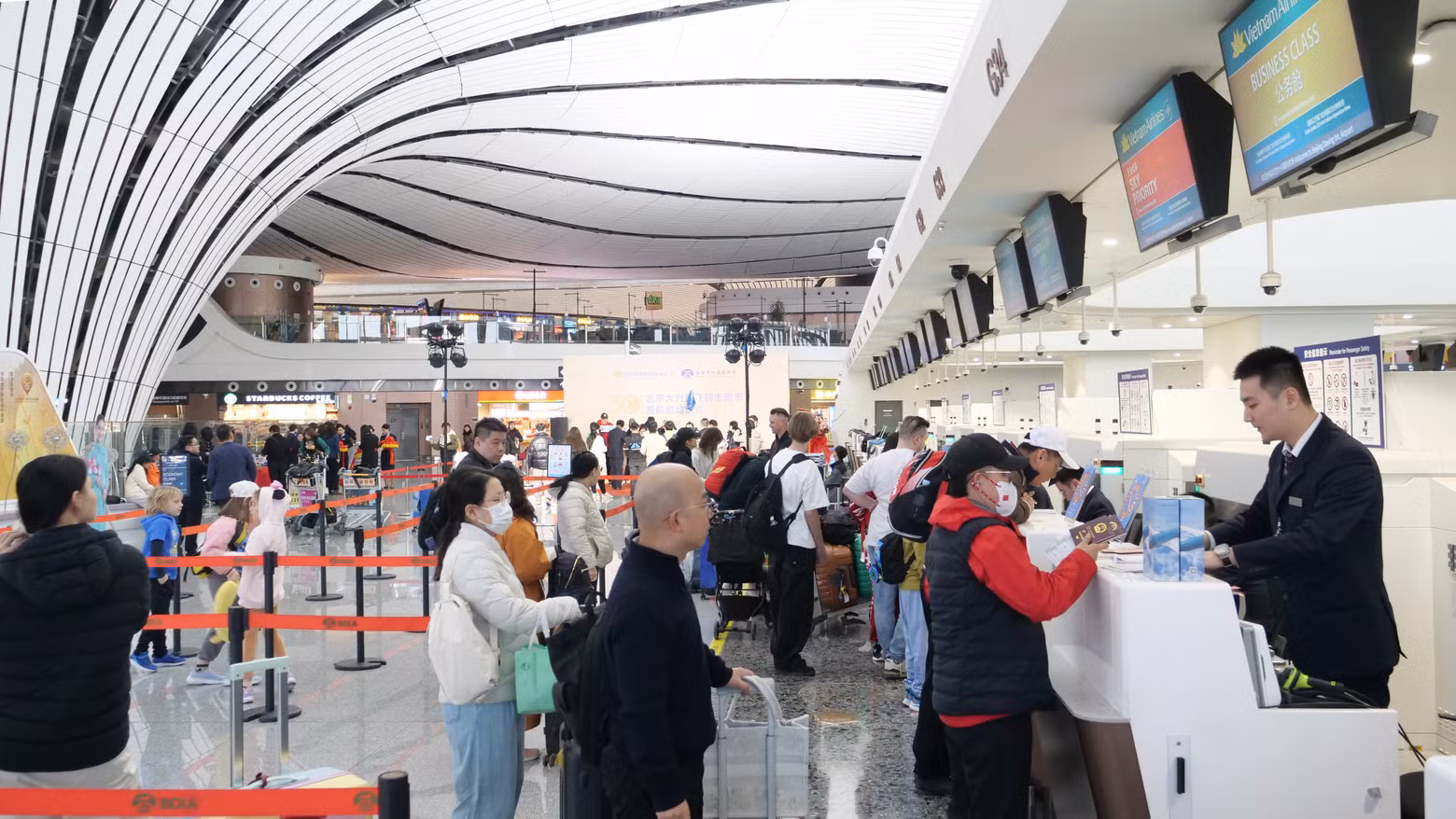 乘客们在北京大兴国际机场的越航柜台办理登机手续。 乘客们在北京大兴国际机场的越航柜台办理登机手续。