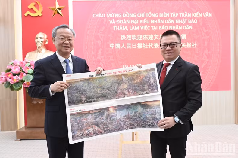 黎国明同志向陈建文同志介绍《奠边府战役》全景图副刊。（裴江 摄）