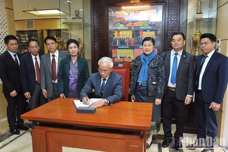 老挝人民革命党中央宣训部部长坎潘·佩亚翁参观《人民报》传统屋并在留言簿上写下了感想。