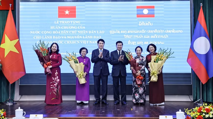 越南国家主席梁强与老挝国家主席通伦·西苏里向荣获勋章的各位同志赠送鲜花。