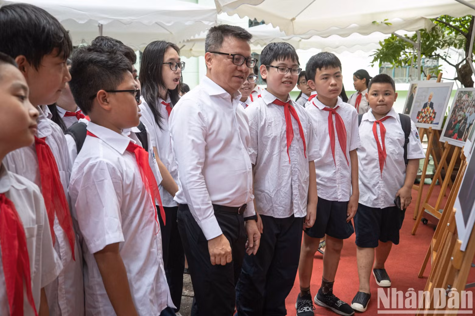 《人民报》社总编辑黎国明向还剑初中学校学生介绍阮富仲总书记图片展。
