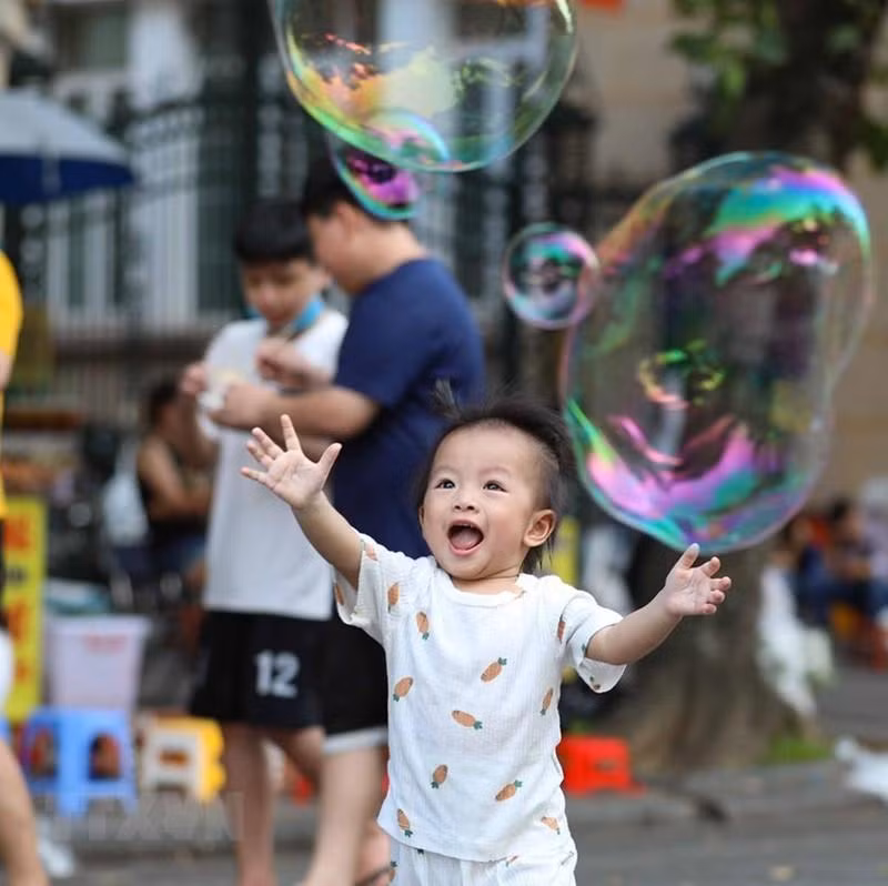小孩在步行街空间乐乐陶陶玩泡泡。
