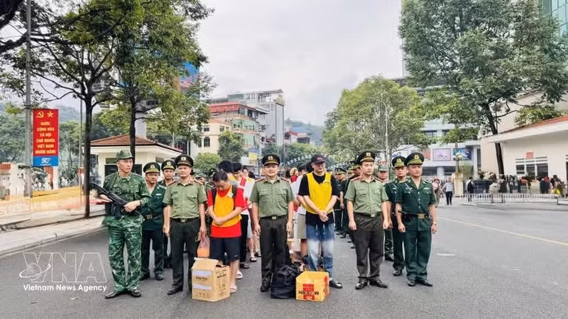 执法力量将19名犯罪嫌疑人押解过老街国际口岸。（图片来源：越通社）