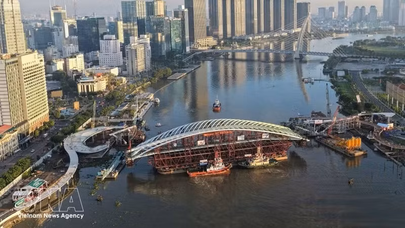 西贡河步行桥项目合龙作业现场全景，装载主跨结构的驳船已就位。（图片来源：越通社）