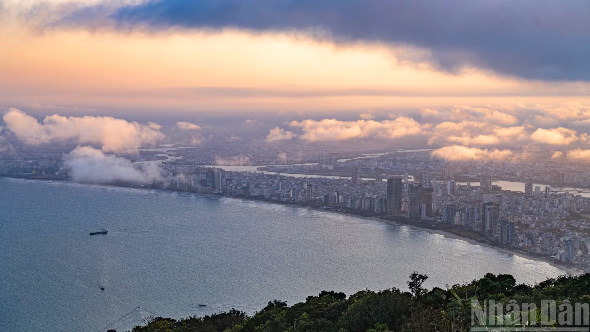 岘港在夕阳映照下隐现于绚丽的粉色云海之中。